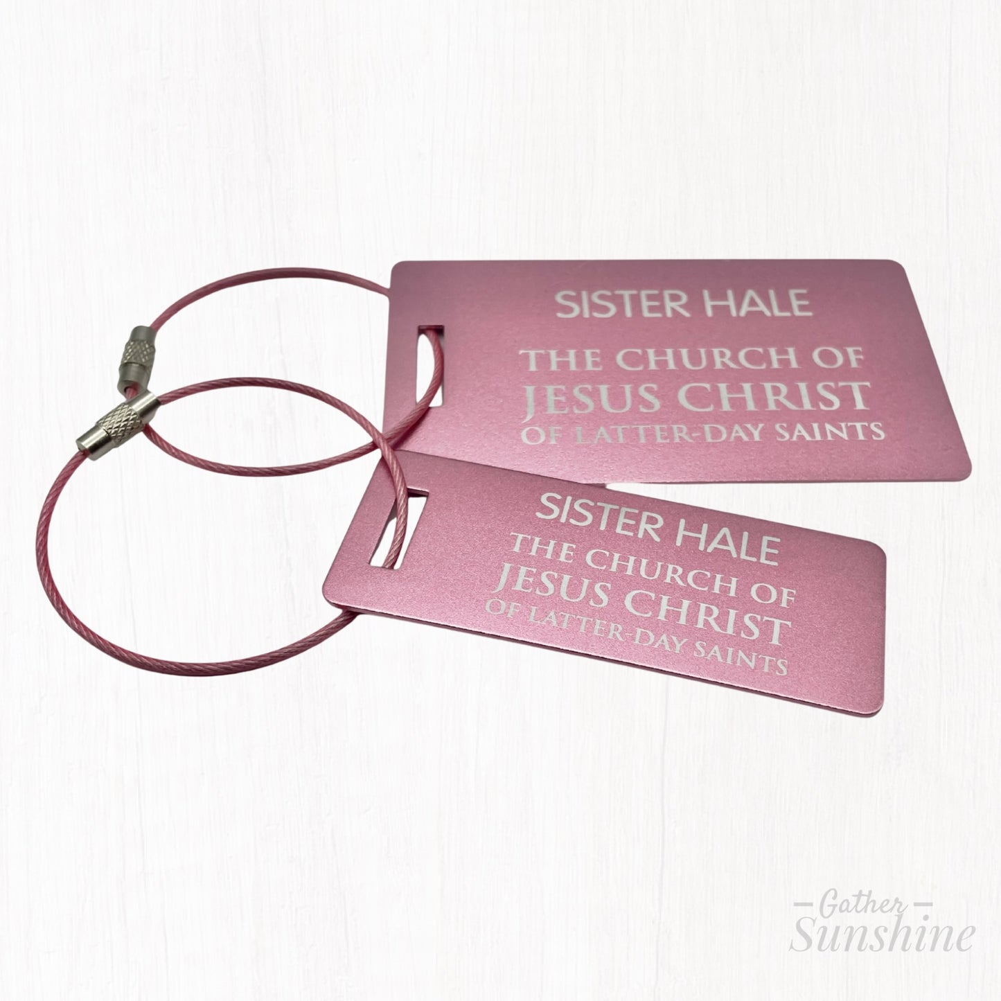 Pink LDS-style missionary small (3x1 inch) and large (3.5x2 inch) luggage tag in English, shown at a different angle on white background. A bold, colorful alternative by GatherSunshine.