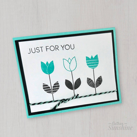 Hand-stamped aqua and black floral greeting card standing upright with layered cardstock, created by Gather Sunshine
