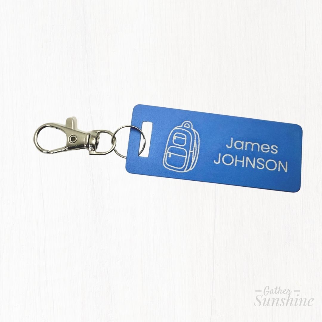Blue zipper pull tag with backpack icon and 'James Johnson' text on a white background