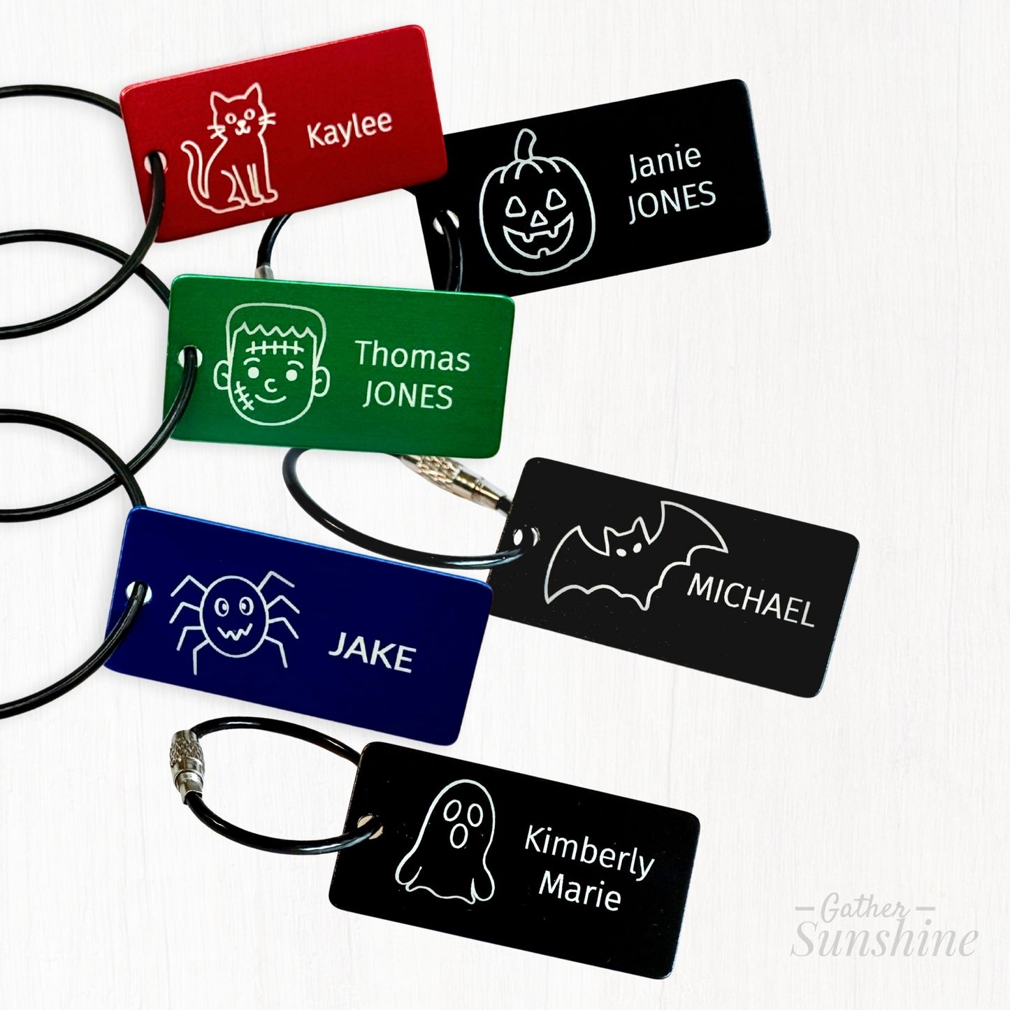 1"x2" tags in four colors. Six engraving design options for custom Halloween name tags including pumpkin, bat, ghost, cat, spider, and Frankenstein by Gather Sunshine.