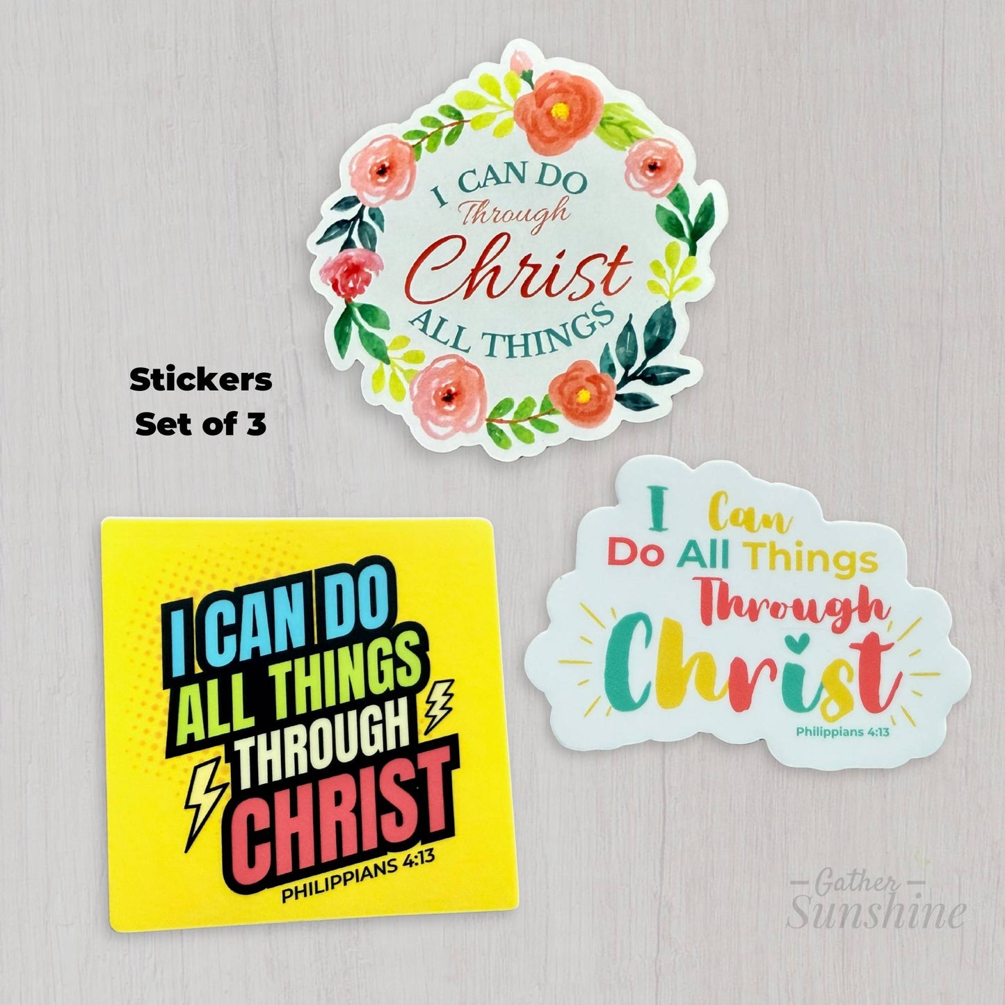 Set of three ‘I Can Do All Things Through Christ’ designs – floral circular pink and green, multicolor script with sunburst, and bold superhero comic style – 3 inch Christian stickers by Gather Sunshine.