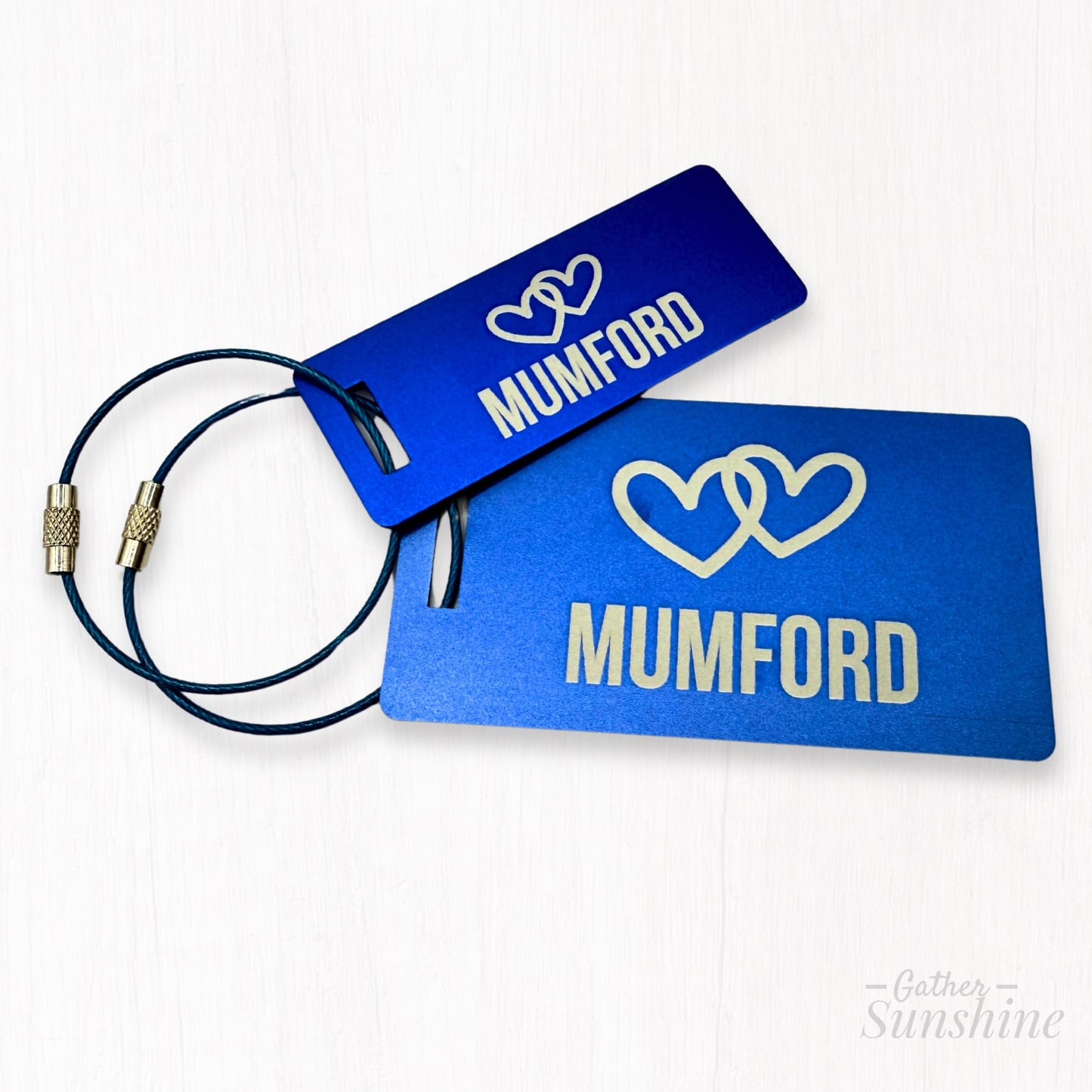 Small (3"x1") and large (3.5"x2") blue luggage tags customized with name of choice and two interlocking hearts. Personalized engraving by Gather Sunshine.