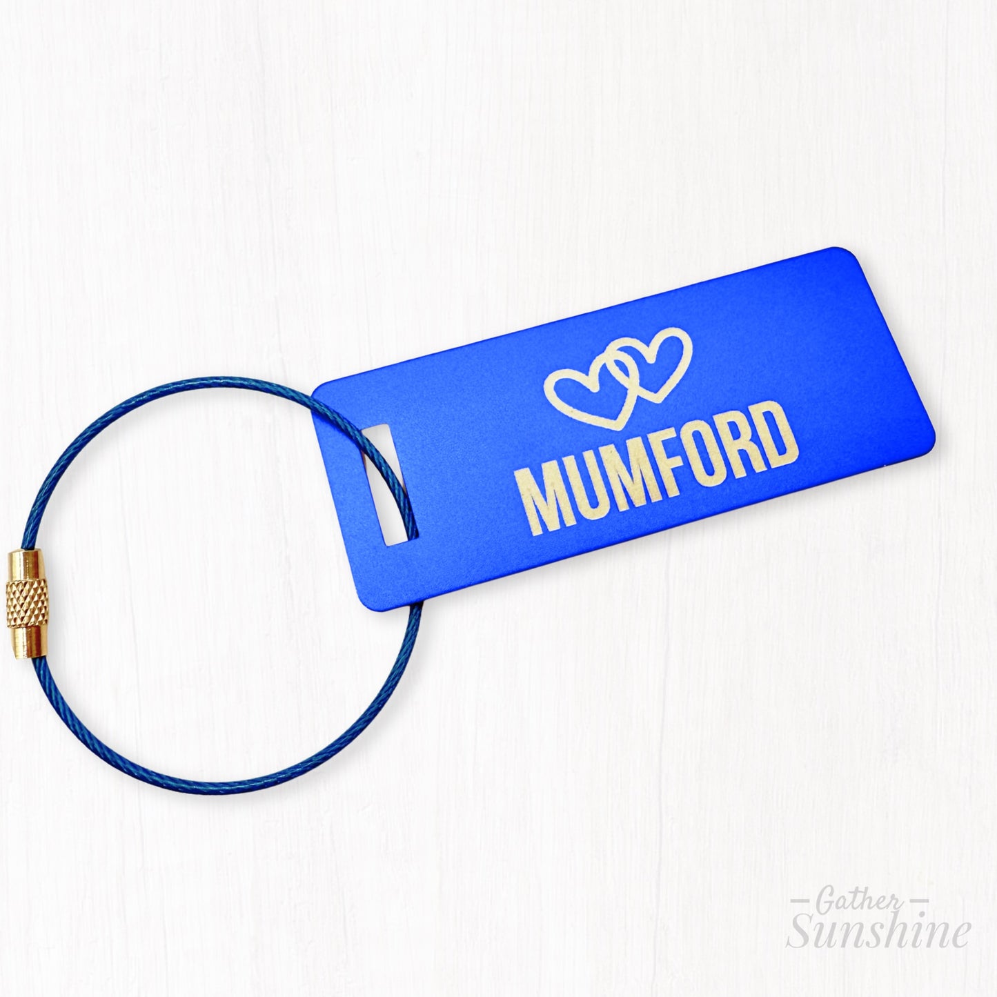 Small (3"x1") blue luggage tag customized with name of choice and two interlocking hearts. Personalized engraving by Gather Sunshine.