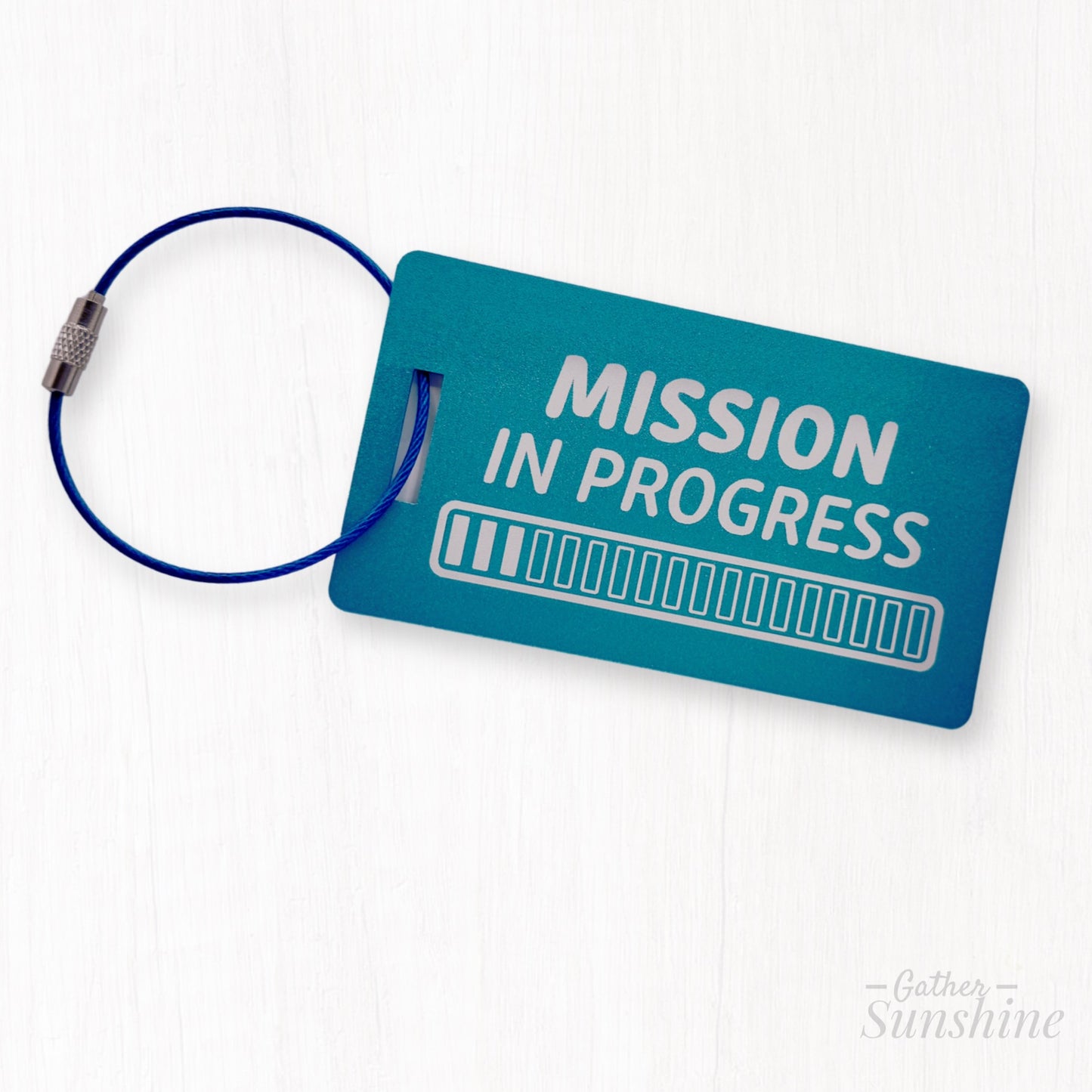 Large teal luggage metal tag engraved with “Mission in Progress” and 18 progress bars. LDS mission gift by GatherSunshine.