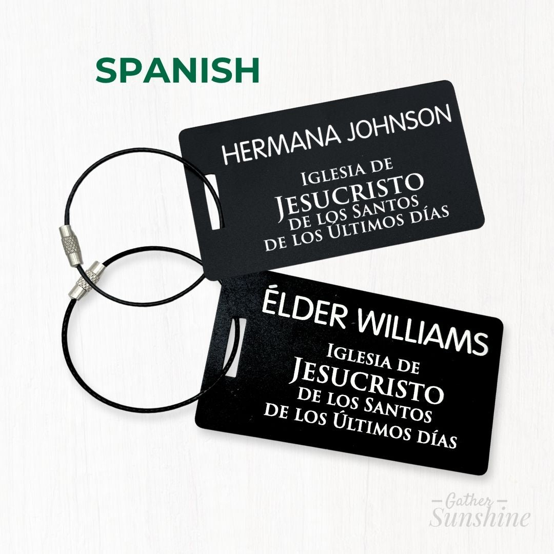 Two black large luggage tags (3.5x2 inch) styled after LDS missionary name tags in Spanish — one engraved 'Hermana Johnson' and 'Élder Williams'. Travel-ready gift by GatherSunshine.