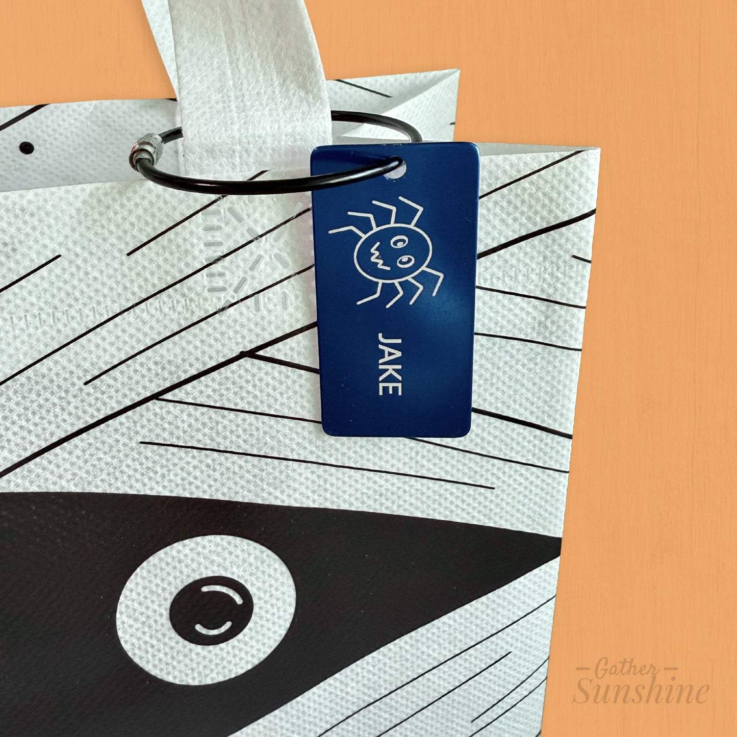 White mummy face trick-or-treat bag with engraved spider name tag personalized with child’s name, Gather Sunshine.