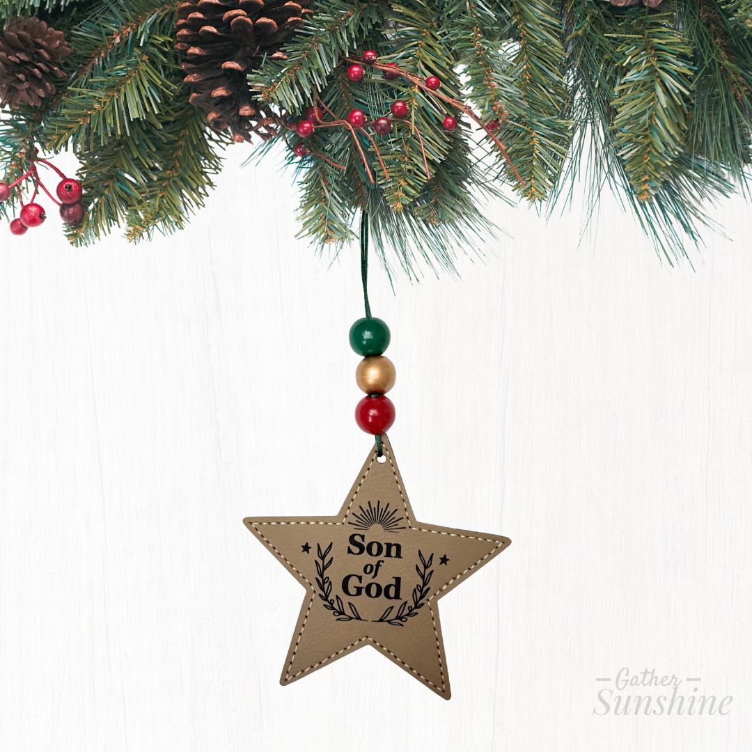 Star-shaped ornament with 'Son of God' text hanging from Christmas tree by Gather Sunshine.