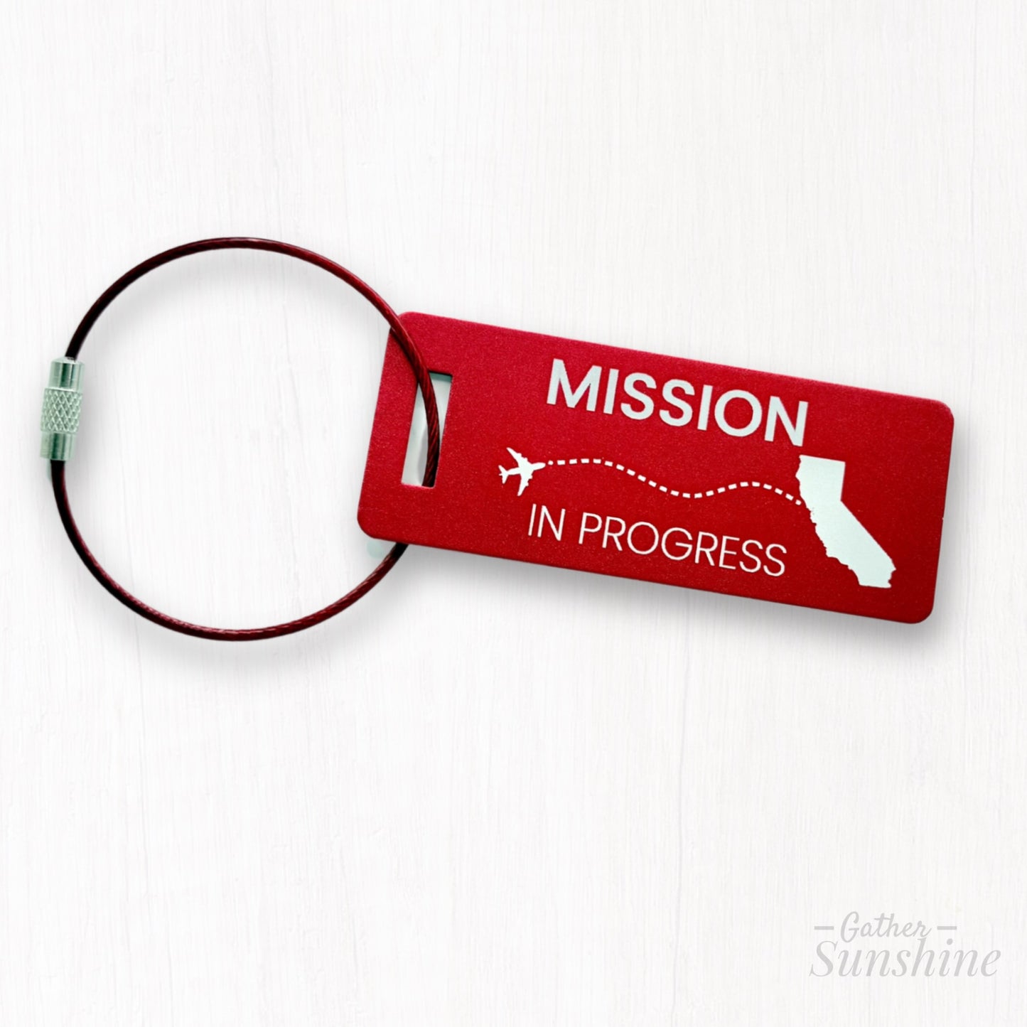 Small red engraved luggage tag with “Mission in Progress” and dotted-line airplane flying toward California; perfect for LDS missionaries.