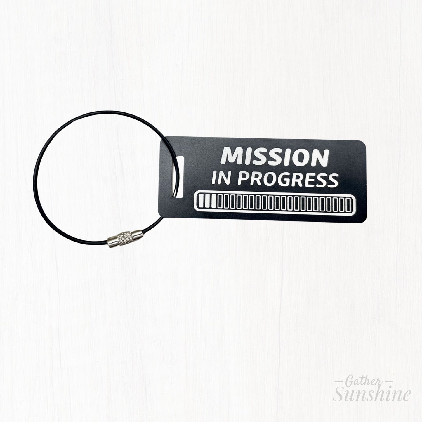 Small black 3x1 inch “Mission in Progress” tag featuring an engraved 24 progress bars design. Personalized LDS missionary gift by GatherSunshine.
