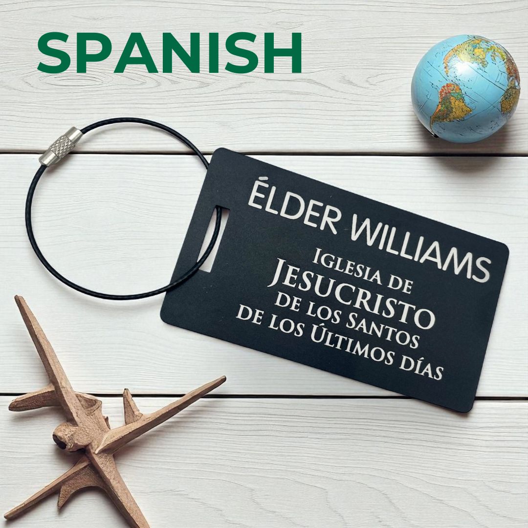 A black large luggage tag (3.5x2 inch) styled after LDS missionary name tags in Spanish - personalized engraved with name of missionary. Travel-ready gift by GatherSunshine.