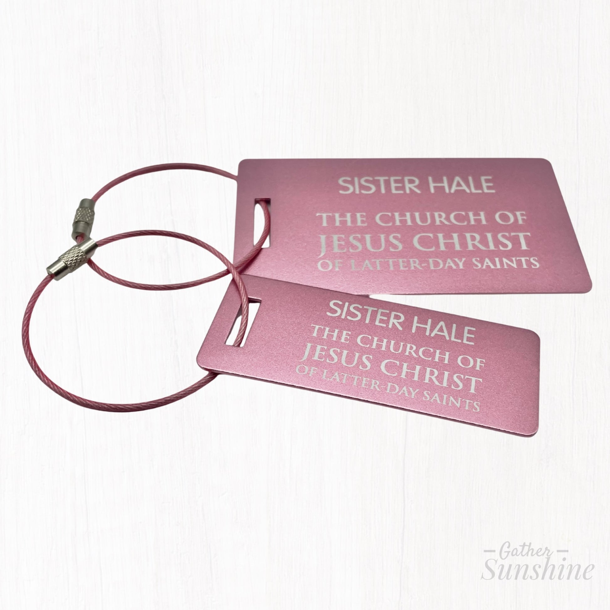 Pink LDS-style missionary small (3x1 inch) and large (3.5x2 inch) luggage tag in English, shown at a different angle on white background. A bold, colorful alternative by GatherSunshine.