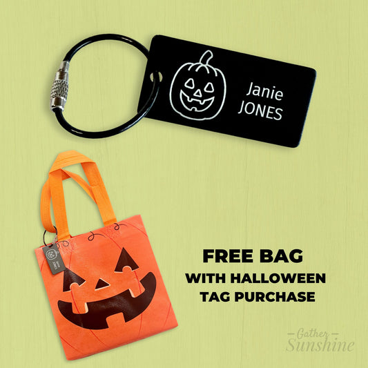 Orange Halloween bag with black pumpkin face design and a black tag with white pumpkin face on a green background by Gather Sunshine.