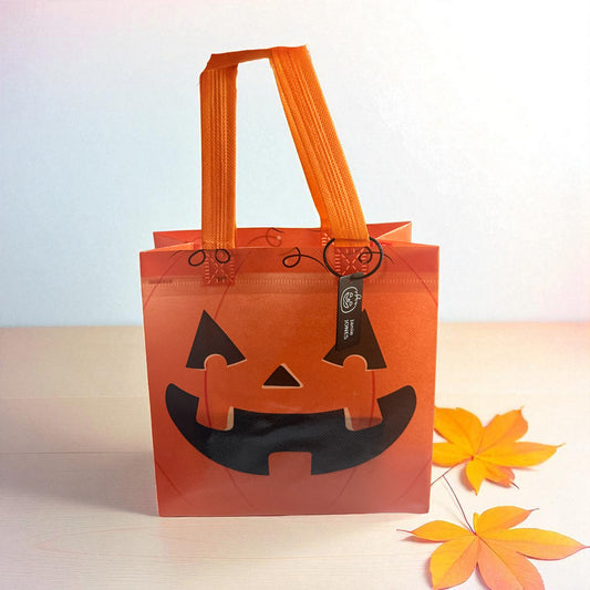 Orange pumpkin trick-or-treat bag with personalized engraved Halloween tag by Gather Sunshine.