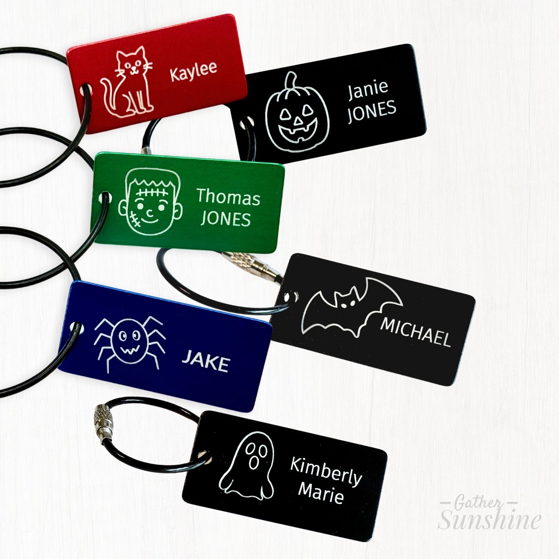 1"x2" tags in four colors. Six engraving design options for custom Halloween name tags including pumpkin, bat, ghost, cat, spider, and Frankenstein by Gather Sunshine.