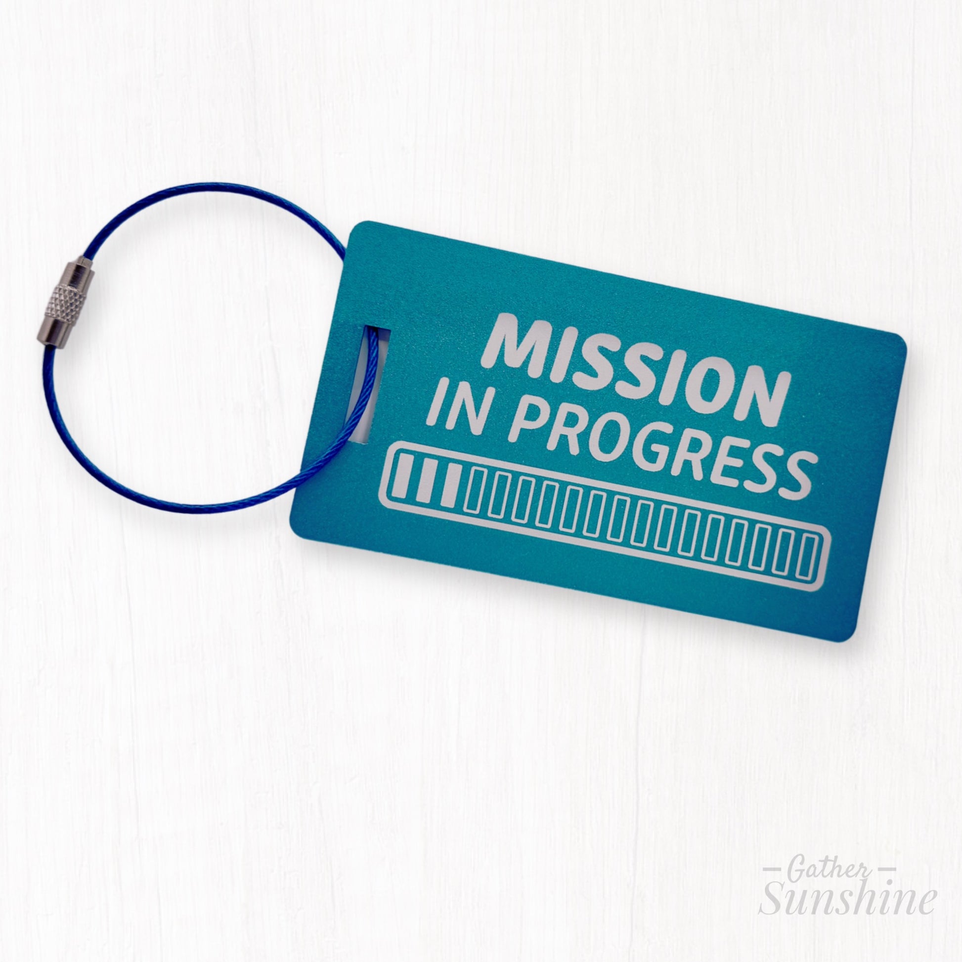 Large teal luggage metal tag engraved with “Mission in Progress” and 18 progress bars. LDS mission gift by GatherSunshine.