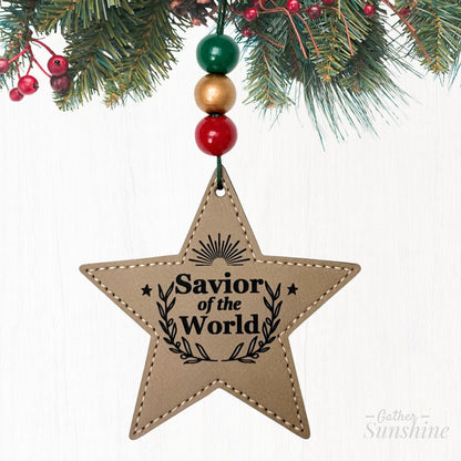 Star-shaped ornament with 'Savior of the World' text, hanging from Christmas tree by Gather Sunshine.