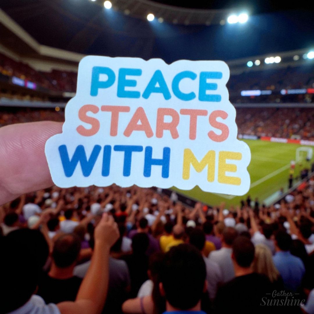 Peace Starts With Me vinyl sticker held up at a sports stadium, reminding to share kindness and calm wherever you are – by Gathersunshine