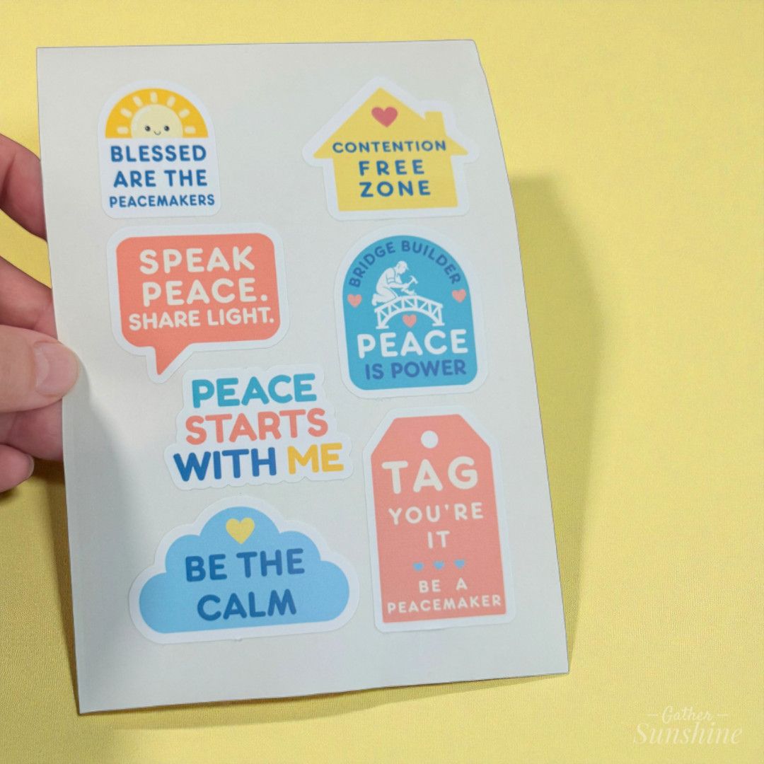 Hand holding a Peace Starts With Me sticker sheet with uplifting messages about kindness and calm on a warm yellow background by Gathersunshine