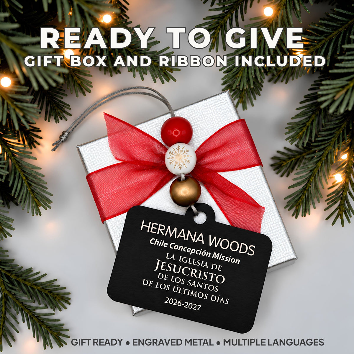 A personalized Christmas gift box with a white textured lid, wrapped in a red ribbon and bow, with a black engraved metal tag. Gift Ready.