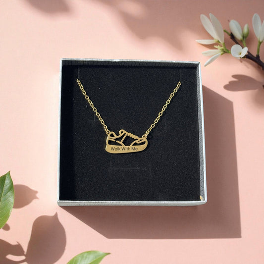 Gold “Walk With Me” necklace in gift box with soft floral shadows - LDS 2026 youth theme jewelry gift by Gather Sunshine.